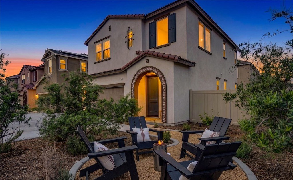 Two story Spanish style Temecula home at dusk with an outdoor fire pit lounge